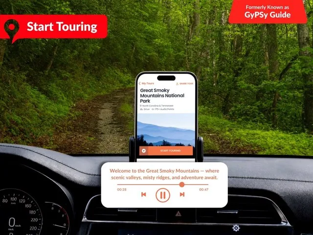 Un smartphone en el salpicadero de un coche mostrando la interfaz de una aplicación de tours.